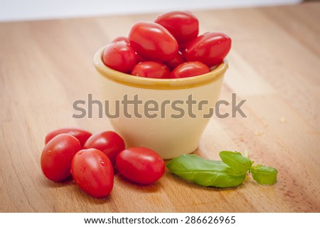 Delicious Grape Tomatoes in a bowl on a cutting board with fresh basil