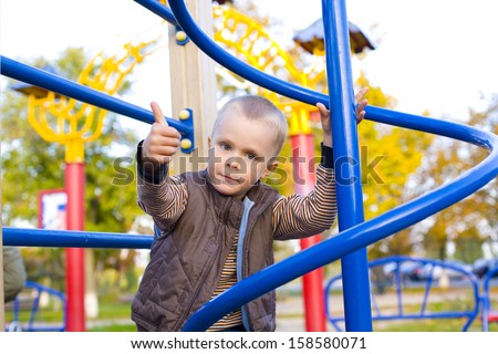 Four year old boy playing on the playground in autumn