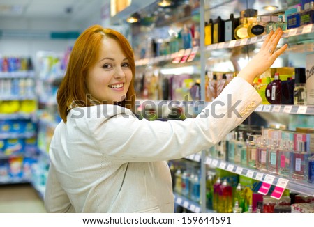 Young woman in shop of cosmetics and perfumery chooses spirits