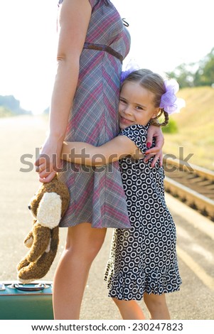 Happy five year old girl hugging her mother\'s legs