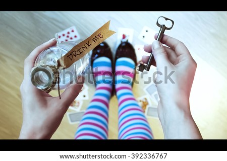 Alice in wonderland. Background. A key and a potion in hands against a  floor