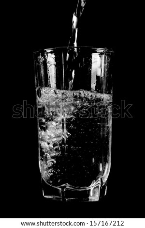 Pouring fresh water in faceted glass. Isolated on black background.