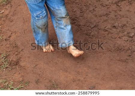 Kid wearing jeans trousers walking on muddy ground