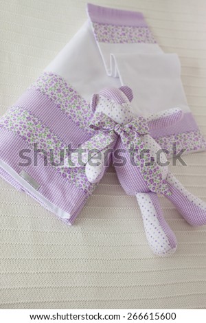 Purple dish cloth and rabbit toy on white linen towel