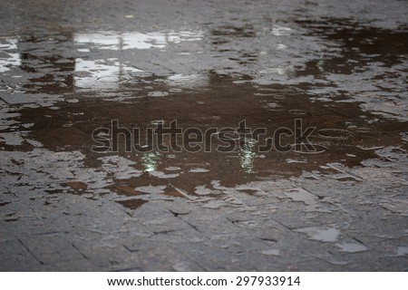 Sidewalk with puddles of water and raindrops