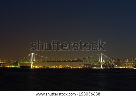 Bridge and night view. The big bridge is lighted up. It is fantastic and sees the bridge. A factory zone is seen on the opposite bank.