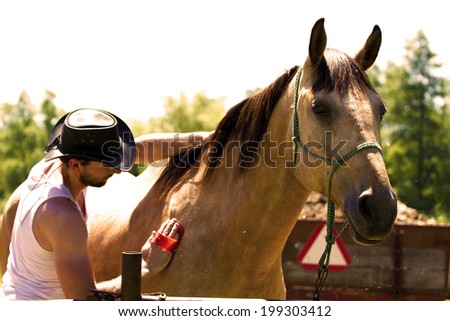 young cowboy cleans horse