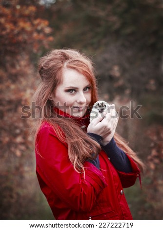 beautiful young woman with cute and funny hedgehog baby in autumn nature