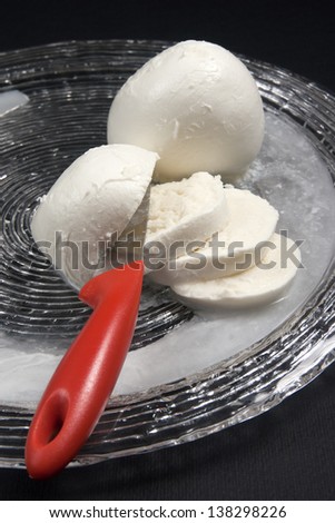 Mozzarella, typical fresh Italian cheese made with buffalo or cow milk in glass dish on a black background