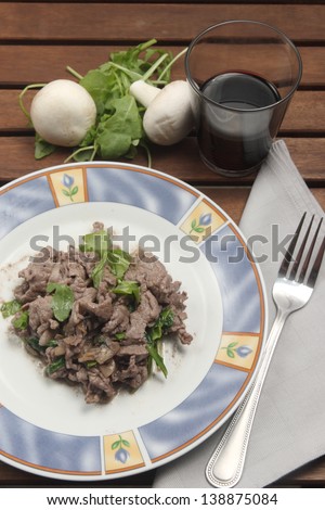 Sliced mushrooms and arugula, A typical dish of traditional Italian cuisine with ingredients, beef, mushrooms arugula.
