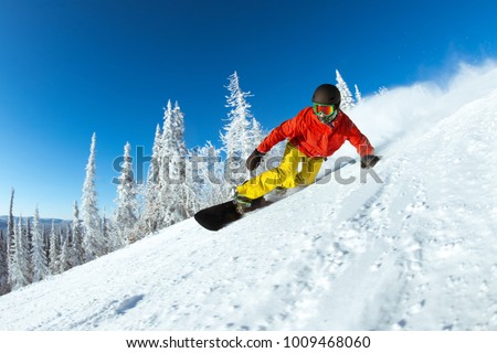 Winter sports photo with very fast snowboarder slides at ski slope