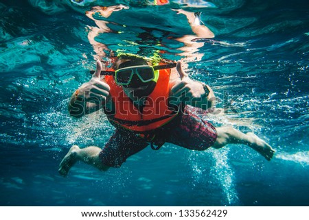 man swimming underwater in a life jacket and a mask for snorkeling