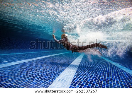 Underwater photo of man jumping in the water dressed in business suit