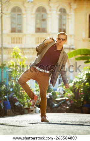 Fashion man dressed like hipster posing on background of old house