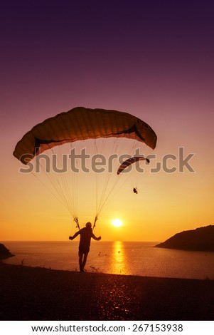 Group of skydivers ready to start flying on background of sunset sky and sea