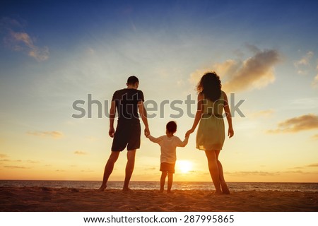 Family of three person is standing on sunset and sea backdrop