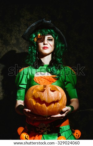 Young girl dressed in pirate costume is holding Halloween pumpkin
