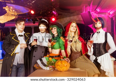 Group of young friends dressed in Halloween costumes are posing at club party