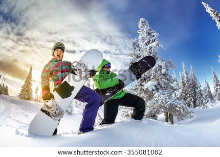 Young couple having fun with snowboards at sunset time. Playing on snowboards like on guitar. Sheregesh resort, Siberia, Russia.