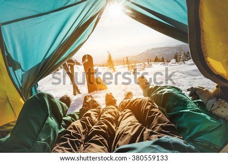 Group of friends snowboarders and skiers relaxing in tent on background of sunset and mountains valley. Sheregesh resort, Siberia, Russia