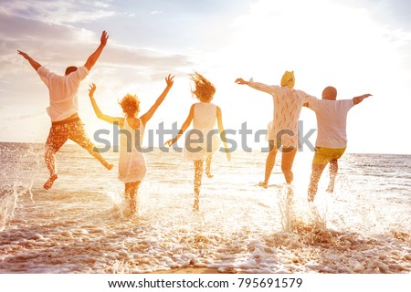 Group of five happy peoples run and jump to sea beach against sunset sun