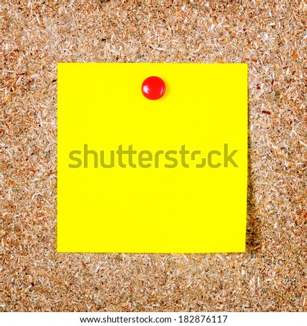 Yellow note paper on a cork board. Closeup