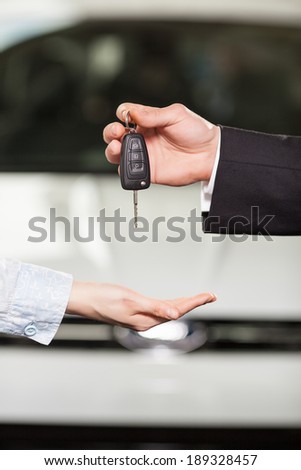 Now this car is yours. Car salesman giving the key to the new car owner