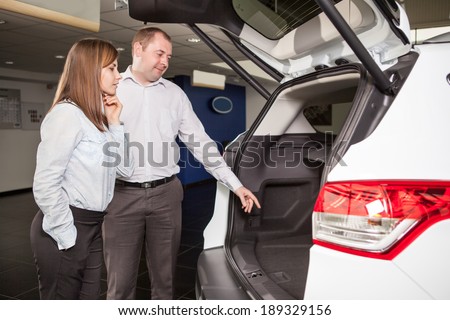 It?is so roomy inside. Handsome young car salesman showing the car trunk to the customer