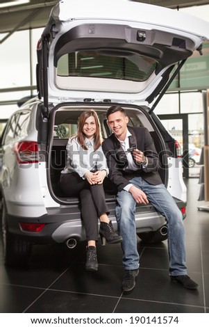 Happy young couple sitting at back of car
