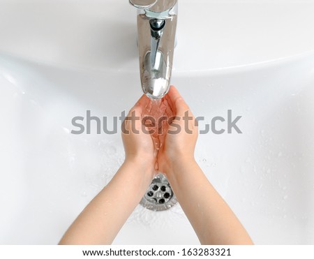 A child washing her hands in a sink with running water