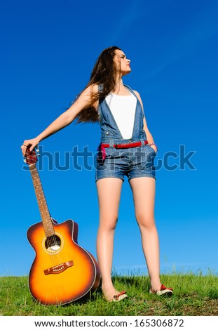 young girl posing leaning on a guitar