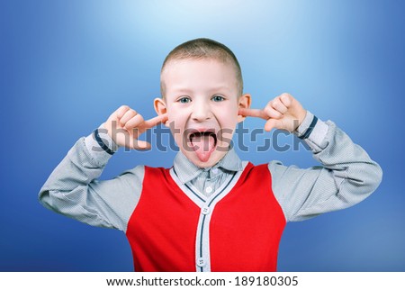 boy showing tongue with fingers in ears