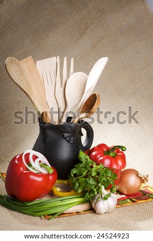 Still life with multicolor vegetables, black jar and wood spoons
