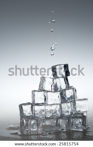 Mineral water drops falling on  frozen crystal transparent ice cubes.