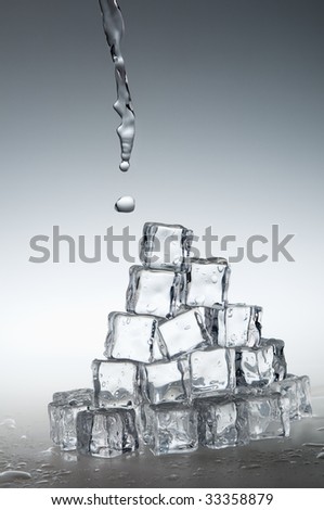 Clear fresh mineral water pouring on frozen crystal transparent ice cubes.