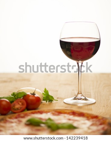 Glass of wine with pizza and tomatoes in white background