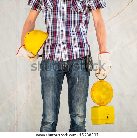Man with white gloves and walkie talkie holding yellow helmet and flashing light