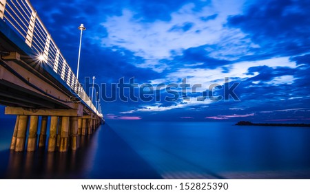Bridge on beach in sunrise and sea wave in Tuscany, Italy