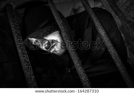 fearful hooded man in jail