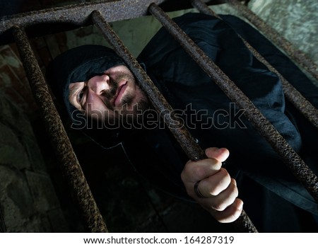 fearful hooded man in jail