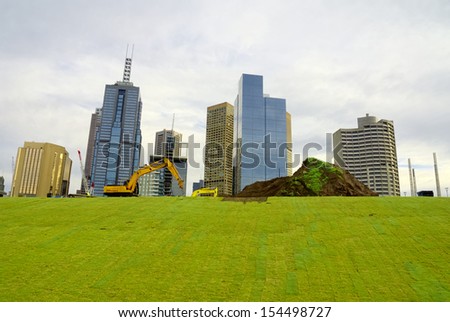 looking up at melbourne city behind a grassy slope under development