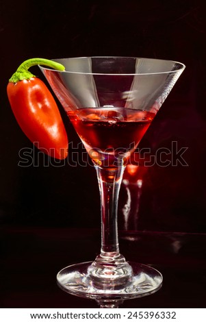 Pepper Cocktail - single cocktail glass with red drink and small red pepper hung on glass.