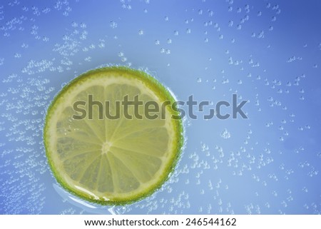 Slice of lemon in sparkling water with blue background