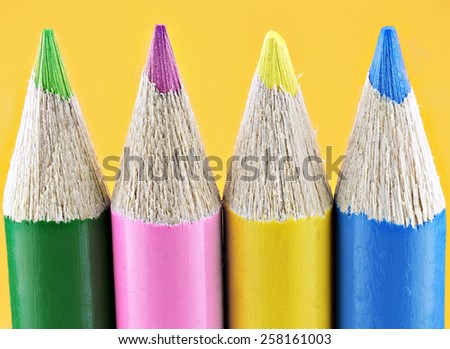 Macro of four colored pencils in a row - green, pink, yellow and blue