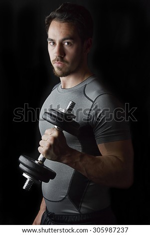 Isolated male working out with weights. Low-key lighting with black background.