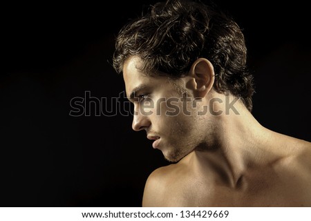 young sexy male looking to the side. Studio shot isolated on black.
