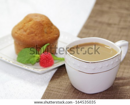 Sweet cake on a brown cloth and cup of white coffee