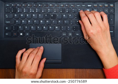 Hands typing text on a laptop keyboard