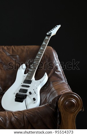 The image shows a leather couch and a white guitar