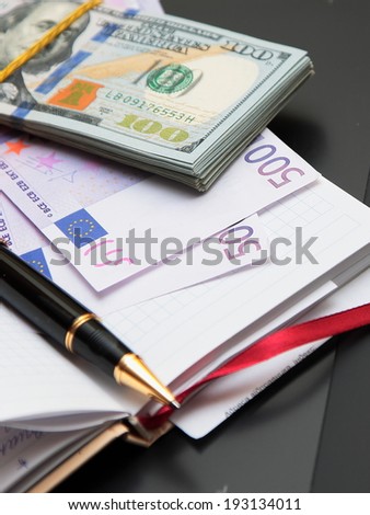 Paper money, notebook, handle Pack of banknotes against a notebook and the handle.